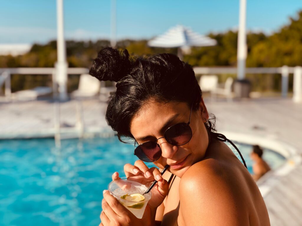 Woman enjoying a sunny day by the pool in Ocean City, relaxing with a drink.